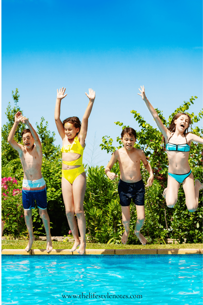How to Have an Organized Summer with Kids. Four kids jumping into a pool at once, with their arms up in the air.