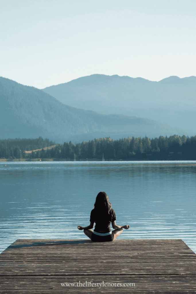 Summer Wellness Reset for Busy Moms. Woman sitting at the end of a dock overlooking a lake and mountains.